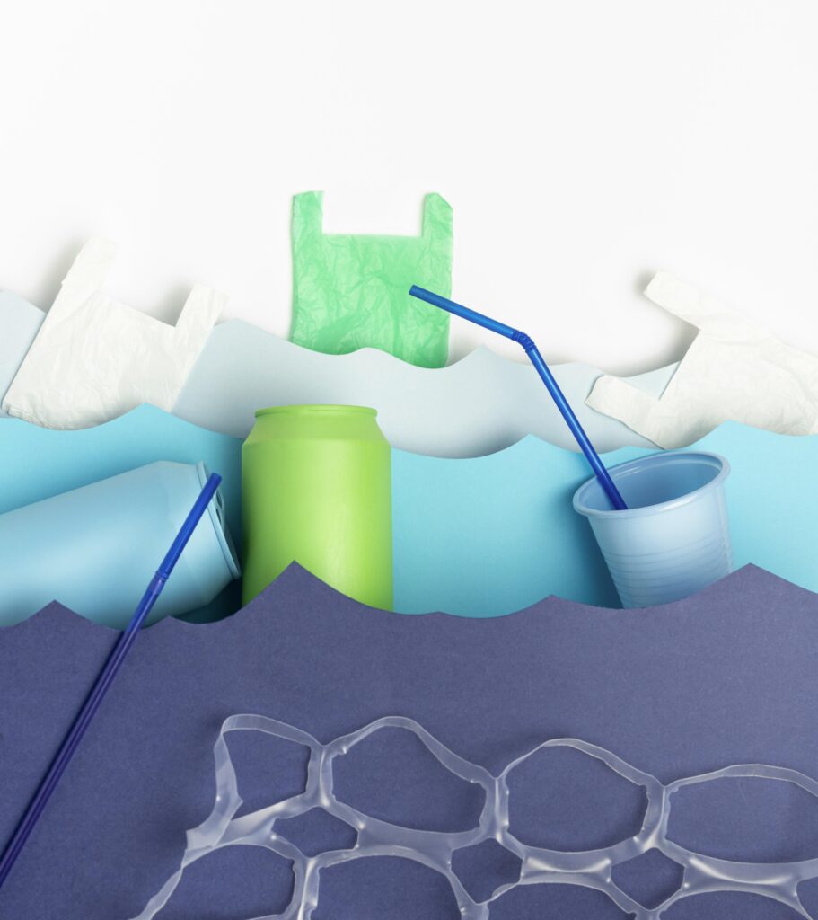 Colorful plastic waste like straws, cans, and bags forming ocean wave shapes, highlighting marine pollution.